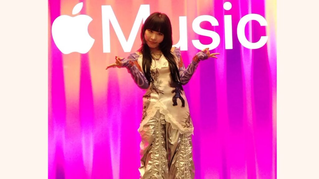 アップルミュージックのポスターの前でポーズをとる紫今